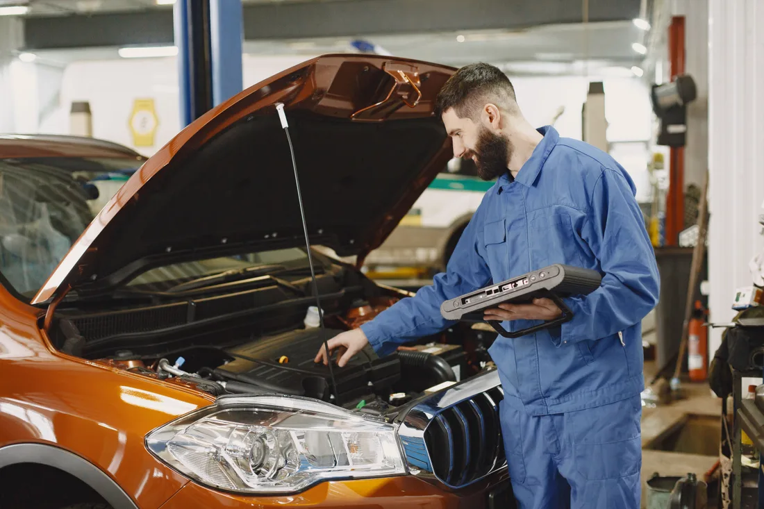 Mechanic inspecting a vehicle under its open hood