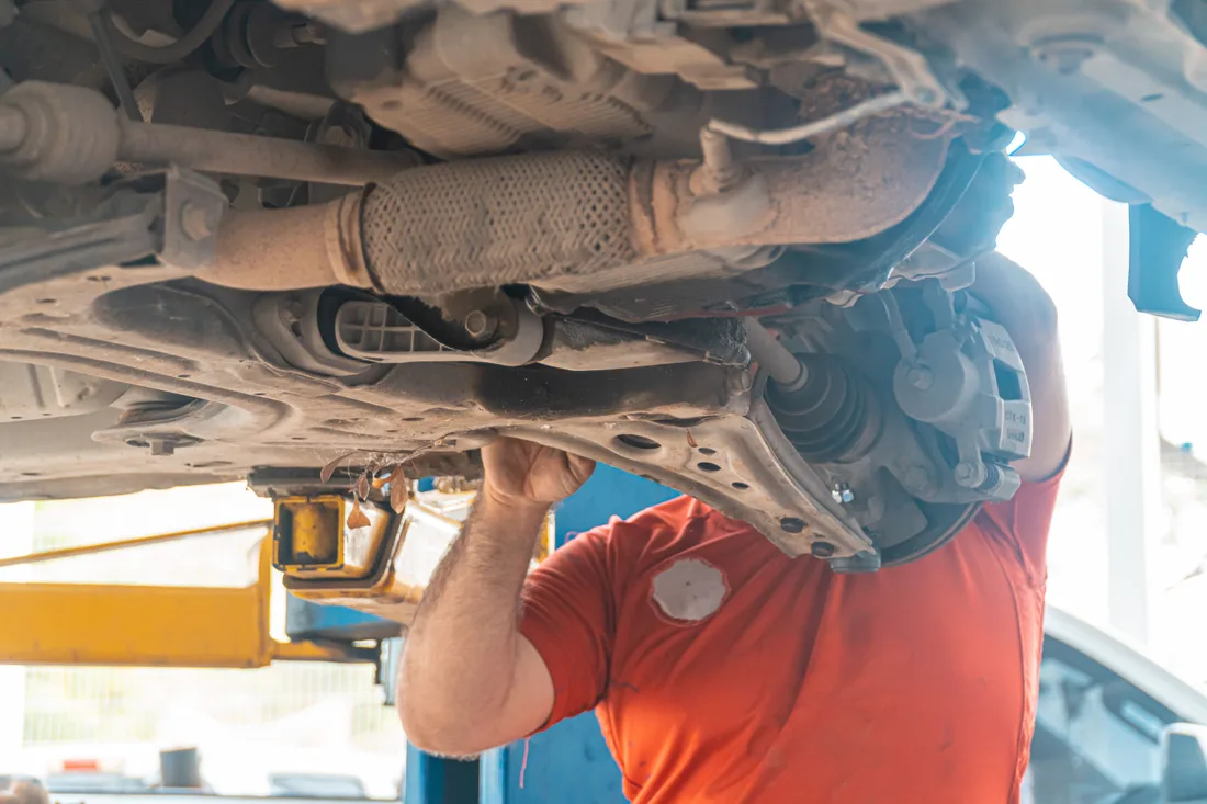 Mechanic inspecting a raised vehicle’s suspension and undercarriage